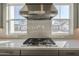 Modern kitchen featuring a range top on white countertop, stainless steel range hood, and sunlit view at 10972 N Hershey St, Surprise, AZ 85388