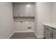 Laundry room with gray cabinets, white quartz countertops, and gray wood look tile floors at 10972 N Hershey St, Surprise, AZ 85388