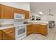 Cozy kitchen area with wood cabinets, white appliances, and an open view of living space at 15203 N 28Th Pl, Phoenix, AZ 85032