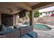 Inviting covered patio with plush seating overlooking the pool with a rock waterfall and lush backyard at 15658 W Cortez St, Surprise, AZ 85379