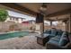 Covered patio featuring comfortable seating, outdoor kitchen, and a refreshing pool with rock waterfall features at 15658 W Cortez St, Surprise, AZ 85379