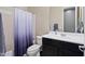 This bathroom offers a shower-tub combo with a white and purple shower curtain and dark brown cabinets at 15658 W Cortez St, Surprise, AZ 85379