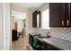 Home office featuring granite countertops, stylish backsplash, wood floors and dark cabinetry with a view to the living room at 15658 W Cortez St, Surprise, AZ 85379