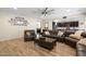 Well-lit living room featuring a large leather sectional, wood-look flooring, and seamlessly flows into the dining area at 15658 W Cortez St, Surprise, AZ 85379