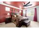 Main bedroom featuring a bold red accent wall and ceiling, ceiling fan, and a well-made bed at 15658 W Cortez St, Surprise, AZ 85379