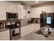 Well-equipped kitchen featuring stainless steel appliances, white cabinets, a mosaic backsplash, and a central island at 16648 W Jenan Dr, Surprise, AZ 85388