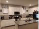 Bright kitchen with white cabinetry, mosaic backsplash, stainless steel appliances, and a central island at 16648 W Jenan Dr, Surprise, AZ 85388