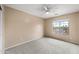 Neutral bedroom with large window bringing in great natural light and a white ceiling fan at 17771 W Caribbean Ln, Surprise, AZ 85388