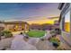 Landscaped backyard with pavers, desert plants, artificial turf, and a covered outdoor kitchen area at 18097 W Santa Alberta Ln, Goodyear, AZ 85338