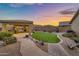 Landscaped backyard with pavers, desert plants, artificial turf, and a covered outdoor kitchen area at 18097 W Santa Alberta Ln, Goodyear, AZ 85338