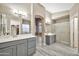 Bathroom featuring a dual sink vanity with gray cabinets, modern lighting, and a glass enclosed shower at 18097 W Santa Alberta Ln, Goodyear, AZ 85338