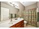 Bathroom with decorative shower curtain, wood vanity, and a large mirror at 18097 W Santa Alberta Ln, Goodyear, AZ 85338