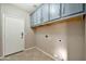 Functional laundry room with overhead cabinets and tile flooring at 18097 W Santa Alberta Ln, Goodyear, AZ 85338