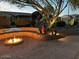 Backyard with a glowing gas fire pit, surrounded by a stone seat wall at 18670 N Rincon Ct, Surprise, AZ 85387