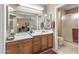 Bright bathroom with wood cabinets, mirrors, and a walk-in shower, perfect for relaxation and convenience at 19503 N 142Nd Dr, Sun City West, AZ 85375