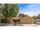 Traditional-style home with desert landscaping, mature trees, and a two-car garage provides great curb appeal at 19503 N 142Nd Dr, Sun City West, AZ 85375