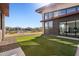 View of modern home's backyard featuring artificial turf, large windows, and views of adjacent houses at 21056 N 58Th St, Phoenix, AZ 85054