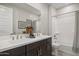 Elegant bathroom featuring double sinks, a dark vanity, a large mirror, and a shower-tub combo at 21112 N 58Th St, Phoenix, AZ 85054