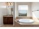 Luxurious bathroom showcasing a soaking tub with stylish fixtures and a large window with neighborhood views at 2448 E Amber Ct, Gilbert, AZ 85296