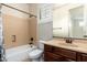 A full bathroom featuring a shower-tub combo, dark wood vanity, and a framed mirror at 2448 E Amber Ct, Gilbert, AZ 85296