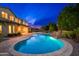 Resort-style pool with a waterfall feature and lush landscaping under a twilight sky at 2448 E Amber Ct, Gilbert, AZ 85296