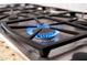 Close up of a gas range stove top with flame lit burner at 2448 E Amber Ct, Gilbert, AZ 85296