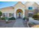 Elegant home entrance featuring a unique stone facade, arched doorway, and beautifully landscaped surroundings at 2467 E Page Ave, Gilbert, AZ 85234