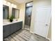 Bathroom with dual sinks, gray cabinetry, large mirrors, and a tiled shower at 29810 W Bellview St, Buckeye, AZ 85396