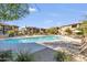 Community pool surrounded by well-maintained landscaping, lounge chairs, and umbrellas at 33575 N Dove Lakes Dr # 2036, Cave Creek, AZ 85331