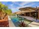 Inviting pool and patio area with lush landscaping and shade umbrella providing an oasis for outdoor enjoyment at 3768 N 162Nd Ln, Goodyear, AZ 85395