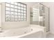 Bright bathroom features a tub, glass block window, and separate glass enclosed shower at 4255 E Cloudburst Ct, Gilbert, AZ 85297