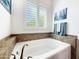 Bright white soaking tub with bronze fixtures and tiled surround underneath a window at 6039 E Sienna Bouquet Pl, Cave Creek, AZ 85331