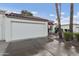 Attached two-car garage featuring a white door and beautiful landscaping, with a glimpse of the home's red tile roof at 617 S Palo Verde Way, Mesa, AZ 85208