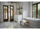 Elegant bathroom featuring a soaking tub, mosaic tile floor, and double doors to the outside at 6737 E Taza Way, Paradise Valley, AZ 85253