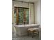 Bright bathroom featuring tiled floors, a standalone tub, and a large wooden window at 6737 E Taza Way, Paradise Valley, AZ 85253