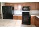 Traditional kitchen featuring wooden cabinets, black appliances, tile countertops and center island at 9213 W Clara Ln, Peoria, AZ 85382