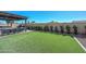 Large backyard showcasing artificial turf, a covered patio with seating, and mature hedges at 10039 W Jasmine Trl, Peoria, AZ 85383