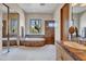 Luxurious main bathroom featuring double sinks, wooden cabinets, a luxurious bathtub, shower and natural sunlight at 10040 E Happy Valley Rd # 249, Scottsdale, AZ 85255