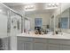 A well-lit primary bathroom featuring a double sink vanity, a glass shower enclosure, and modern fixtures at 10822 W Taylor St, Avondale, AZ 85323