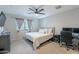 Neutral bedroom with a ceiling fan, a desk, and a large window at 10822 W Taylor St, Avondale, AZ 85323