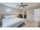 This main bedroom features a ceiling fan, a walk in closet, a desk with a computer setup, and neutral toned carpet at 10822 W Taylor St, Avondale, AZ 85323