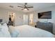 This main bedroom features a walk in closet, a ceiling fan, a TV above a grey dresser, and ensuite access to the primary bathroom at 10822 W Taylor St, Avondale, AZ 85323