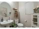 Cozy powder room with pedestal sink, round mirror, and decorative shelving at 10822 W Taylor St, Avondale, AZ 85323