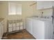 Well-organized laundry room with washer, dryer, storage cabinets, and laundry basket at 11025 N Madison Dr, Sun City, AZ 85351