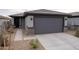 Charming single-story home featuring a gray garage door, stone accents, and desert landscaping at 17353 W Via De Luna Dr, Surprise, AZ 85387