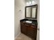 Half bathroom with a dark wood vanity, granite countertop, framed mirror and tiled floor at 18515 N 94Th St, Scottsdale, AZ 85255