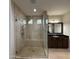 Bathroom featuring a glass-enclosed tiled shower, dark wood vanity with a granite countertop, framed mirror and tiled floor at 18515 N 94Th St, Scottsdale, AZ 85255