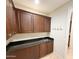 Practical laundry area features dark cabinets, granite countertop, sink, and convenient coat hooks at 18515 N 94Th St, Scottsdale, AZ 85255