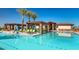 A luxurious community pool area featuring lounge chairs, sunshades, and beautiful palm trees at 24757 N 175 Dr, Surprise, AZ 85387