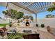 Cozy outdoor fireplace with a seating area, a pergola and beautiful landscaping at 3134 N 145Th Ave, Goodyear, AZ 85395